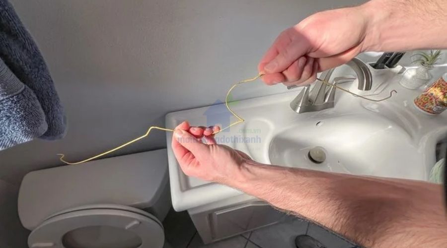 thông tắc bồn cầu bằng móc quần áo uốn cong